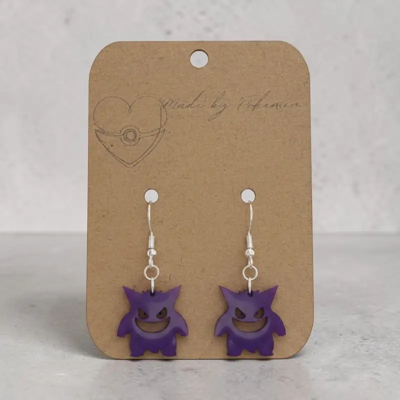 Translucent purple Gengar-inspired earrings with a wide grin, on silver-tone hooks, mounted on a kraft card.